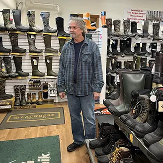 Woman holding a shoe in Farmway Vermont Gears Footwear Department